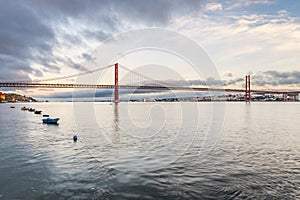 The 25 de Abril suspension bridge over Tagus river in Lisbon, Portugal at sunrise photo