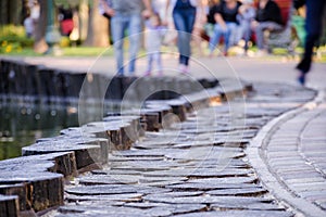 De-focus or blurred photo with people walking along the paved sidewalk in the park.