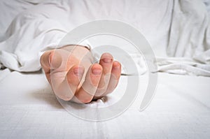 The dead man`s body under white cloth with focus on hand