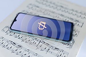 A dead phone lies on a sheet of music