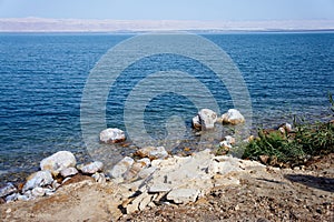 Dead Sea from Jordan side. Salt crystals on huge boulders along coastline. Close-up.  In background is a mountain range in Israel