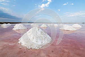 Dead sea salt plains with pyramids of excavated salt. Water colored with pink algae