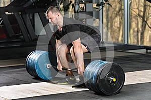 Deadlift attempt. Young man trying to lift heavy barbell