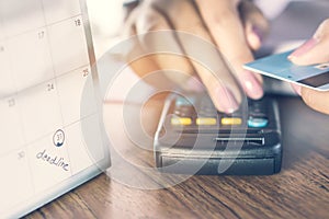 Deadline calendar note with blur background of business woman hand counting her debt on calculator with hand holding credit card