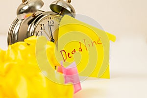 Deadline: Close-up of an alarm clock and sticky notes, emphasizing the urgency