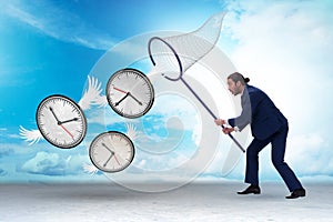 Deadline concept with businessman catching clocks