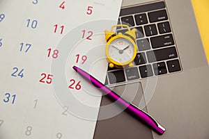 Deadline concept. Laptop and alarm clock, monthly calendar on yellow background. Time is running away