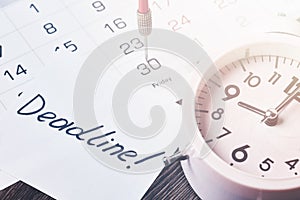 Deadline text on piece of paper, alarm clock and monthly calendar