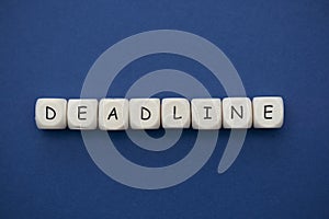 Deadline word on wood blocks over blue background with copy space