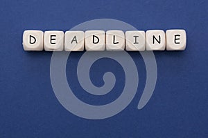 Deadline word on wood blocks over blue background with copy space