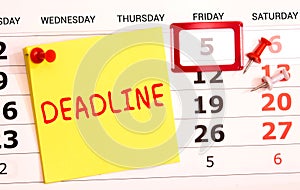 Deadline word written on a post note and hanged on the cork-board with an old pocket watch