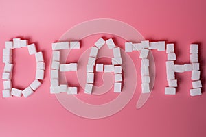 Deadly sugar addiction suggested by spilled white sugar crystals forming a skull on a wooden table