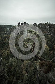 Deadpan dark misty fog mountains from viewpoint of Bastei in Saxon Switzerland, Germany to the mountains at sunrise