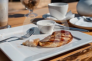 Deadpan image of pancake with honey, sour cream on wooden table with fork, spoon, smartphone and Cup of tea