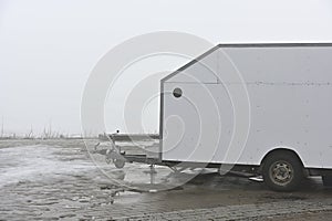 deadpan photo of a white trailer on the shore of a lake in the haze