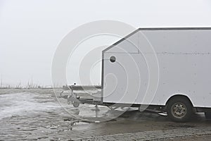deadpan photo of a white trailer on the shore of a lake in the haze photo