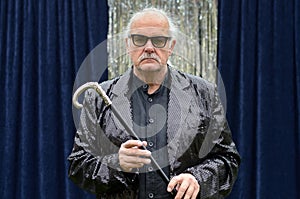 Deadpan stage performer holding a cane photo