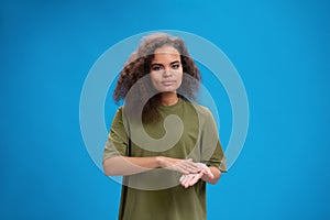 Deaf African American girl using sign language showing hand gesture. Young woman positively looking at camera wearing in
