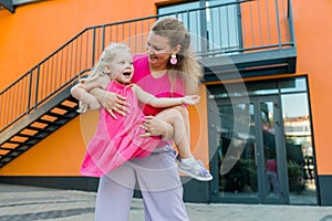 Deaf child with cochlear implant for hearing audio and aid for impairment having fun and laughs with mother outdoor in