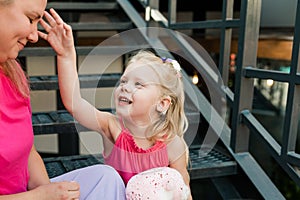 Deaf child with cochlear implant for hearing audio and aid for impairment having fun and laughs with mother outdoor in