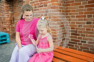 Deaf child with cochlear implant for hearing audio and aid for impairment having fun and laughs with mother outdoor in