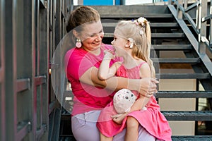 Deaf child with cochlear implant for hearing audio and aid for impairment having fun and laughs with mother outdoor in