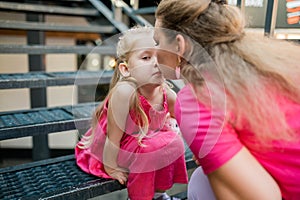 Deaf child with cochlear implant for hearing audio and aid for impairment having fun and laughs with mother outdoor in