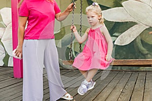 Deaf child with cochlear implant for hearing audio and aid for impairment having fun and laughs with mother outdoor in