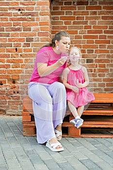 Deaf child with cochlear implant for hearing audio and aid for impairment having fun and laughs with mother outdoor in