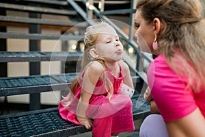 Deaf child with cochlear implant for hearing audio and aid for impairment having fun and laughs with mother outdoor in