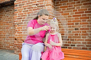 Deaf child with cochlear implant for hearing audio and aid for impairment having fun and laughs with mother outdoor in