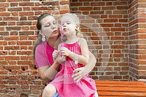 Deaf child with cochlear implant for hearing audio and aid for impairment having fun and laughs with mother outdoor in