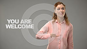 Deaf female saying you are welcome in asl, text on background, interpreter