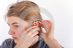 Deaf girl inserting hearing aid