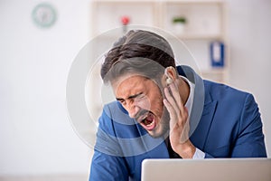 Deaf male employee using hearing aid at workplace