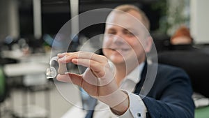 Deaf man working holds hearing aid while sitting in office.