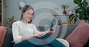 Deaf millennial woman having video call and showing with sign language phrase Fine news whilw sitting on sofa. Female