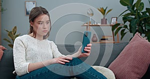 Deaf millennial woman having video call and showing with sign language phrase Terrible news while sitting on sofa