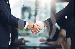 And so the deal was sealed. a businessman and businesswoman shaking hands in a modern office.