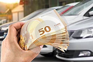 The dealer enters into a contract to buy a new car. shopping concept. A female hand is holding a lot of euro money. Close-up.