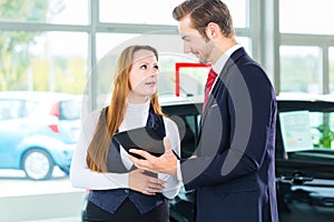 Dealer, female client and auto in car dealership