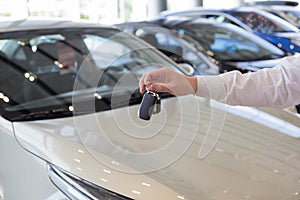 Dealer holding keys to a new car. Modern and prestigious vehicles