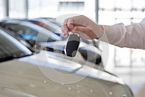 Dealer holding keys to a new car. Modern and prestigious vehicles