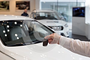 Dealer holding keys to a new car. Modern and prestigious vehicles