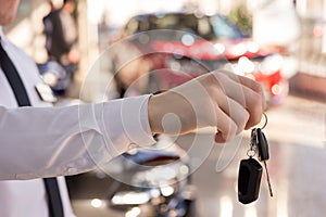 Dealer holding keys to a new car. Modern and prestigious vehicles.