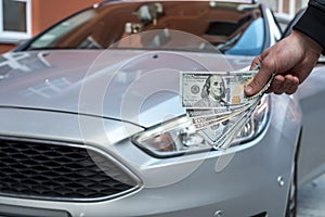 Dealer make agreement to buy a new car, man holding dollar