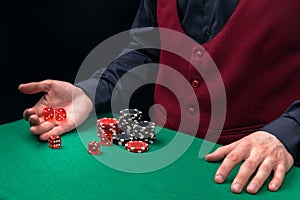 The dealer`s hands roll the dice on the green cloth of the poker table