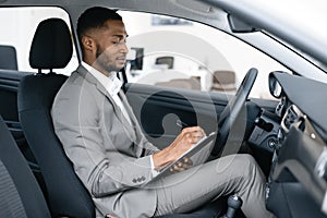Dealer Taking Notes Sitting In Car Checking Automobile In Dealership