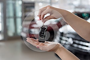 Dealer woman is holding in her hands the keys to the new car. Modern and prestigious vehicles