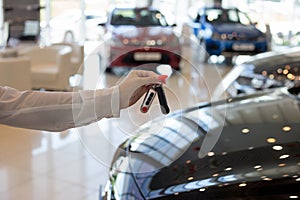 Dealer woman holding keys to a new car. Modern and prestigious vehicles.